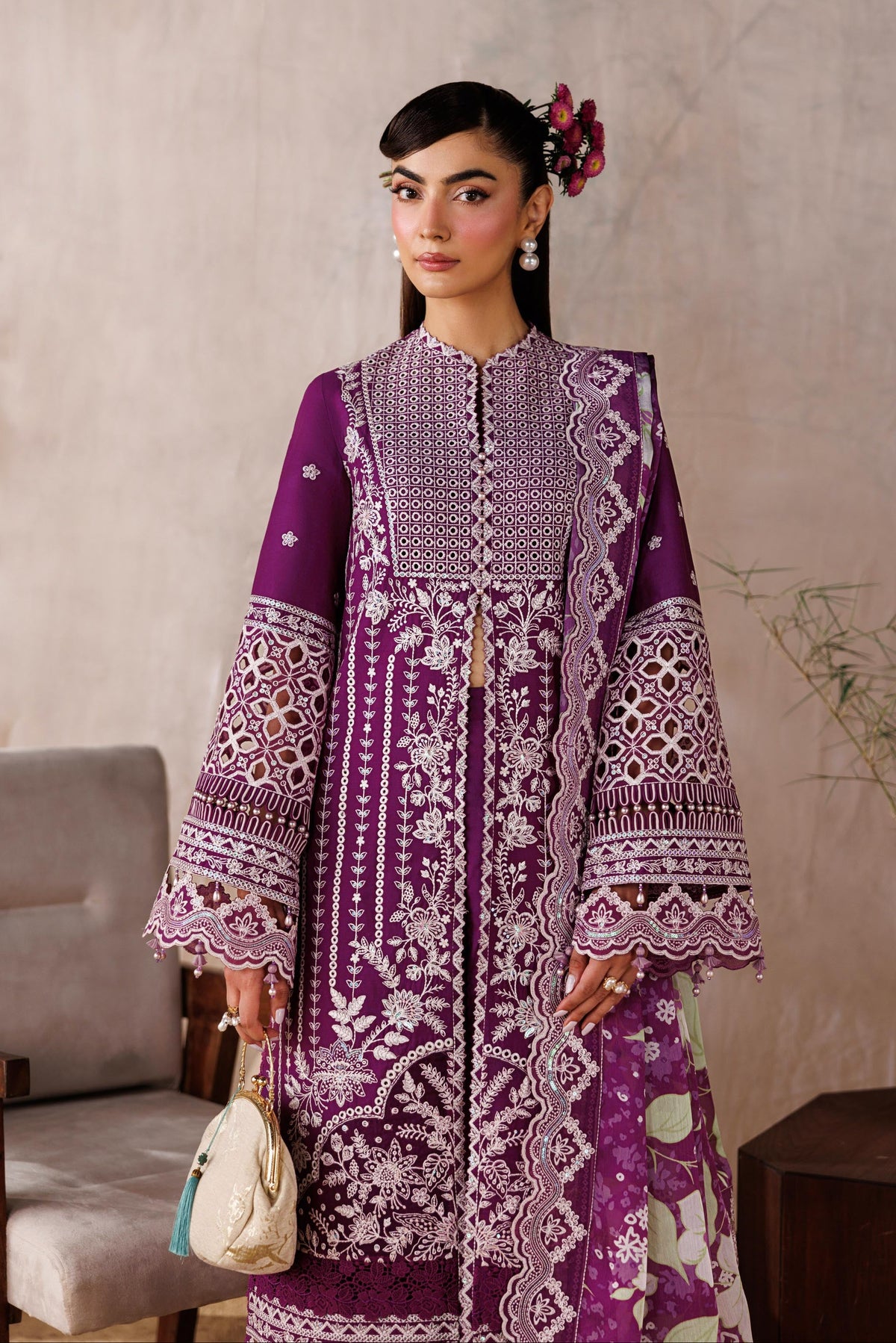 Woman wearing a purple embroidered dress in an indoor setting with a neutral background.