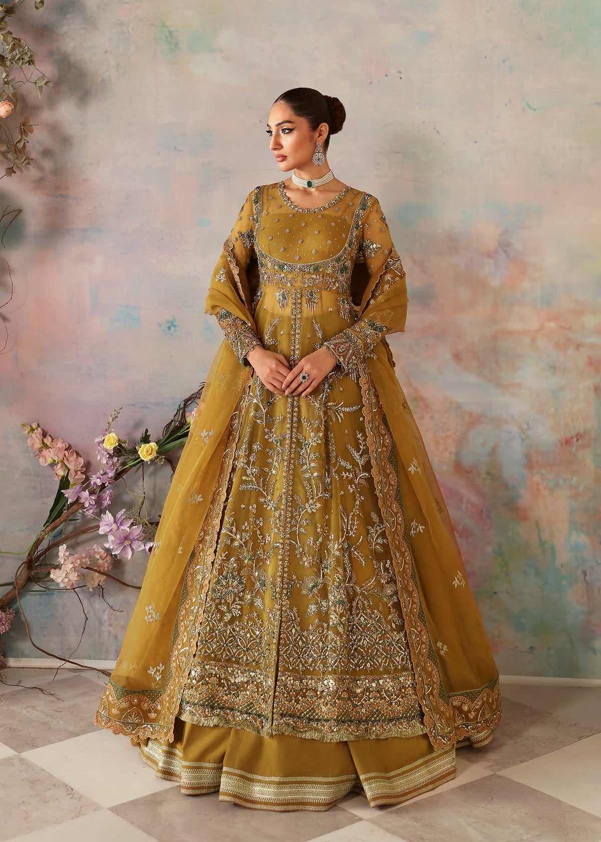A woman wearing a traditional, embroidered yellow and gold dress with organza fabric and hand embellishments.