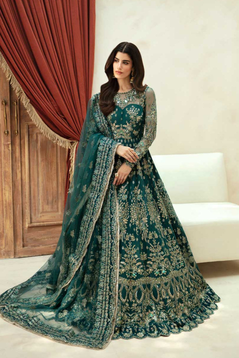 A woman wearing a traditional green and blue embroidered dress with long sleeves and a dupatta.