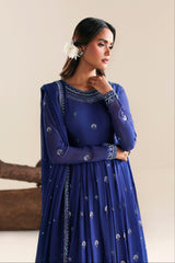 Woman wearing a blue embroidered dress against a beige background