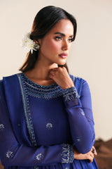 Woman wearing a blue embroidered dress with a neutral background
