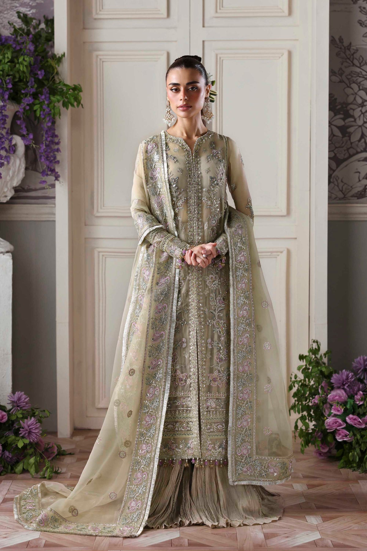 Woman in a traditional outfit with floral decorations in an elegant room.