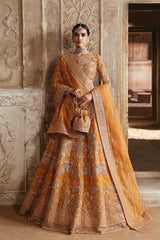 A woman wearing a traditional orange and gold bridal lehenga with intricate embroidery and netting.