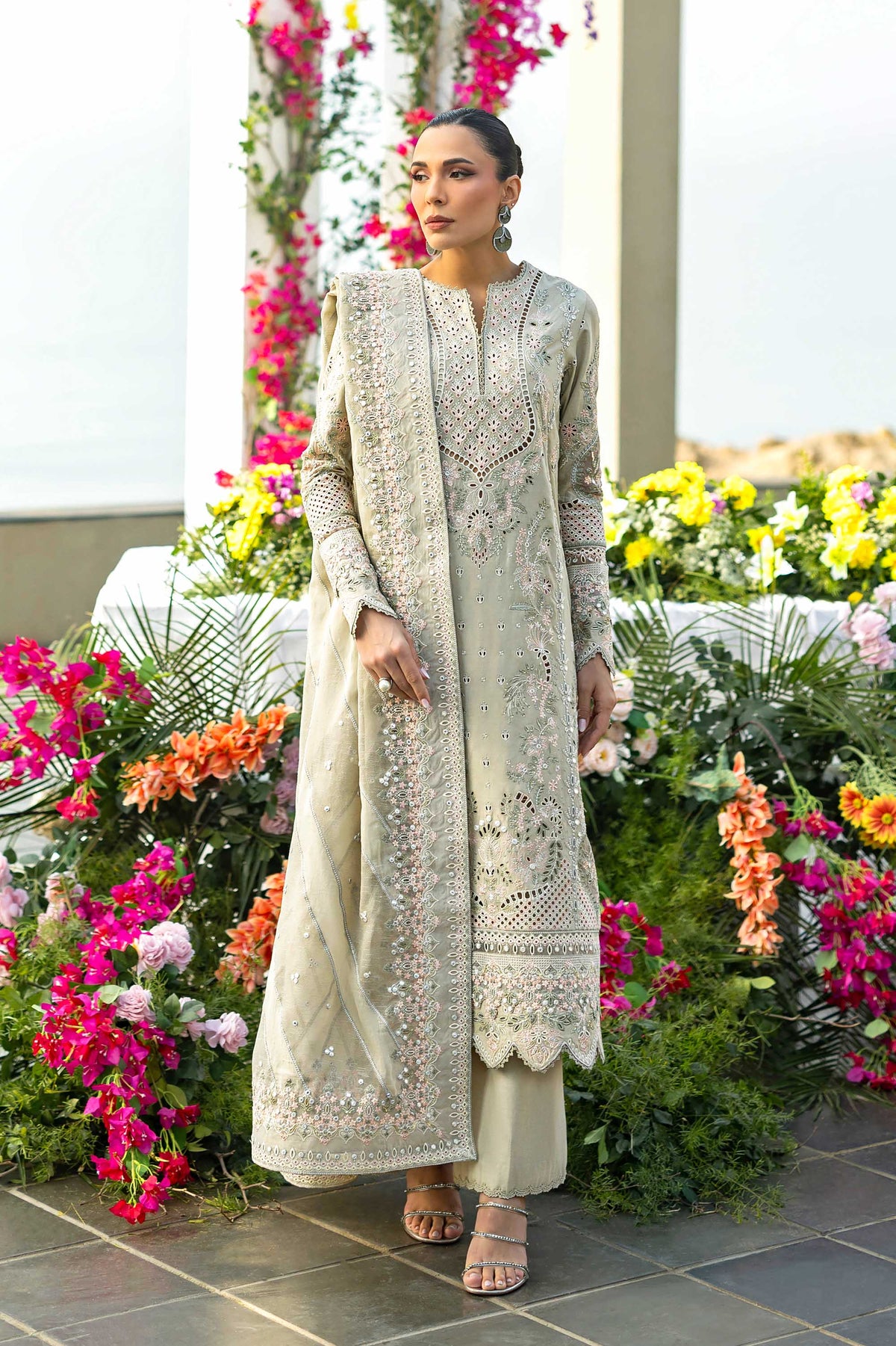 Woman in a traditional outfit standing in front of floral decorations