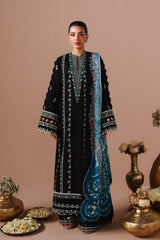 Woman wearing a black and blue embroidered outfit with decorative vases in the background