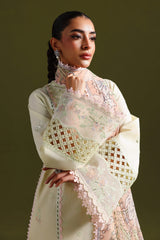 Woman wearing a light-colored embroidered dress against a dark background