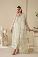 Woman wearing a light green embroidered outfit in a minimalistic room.