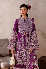 Woman wearing a purple embroidered dress in an indoor setting with a neutral background.