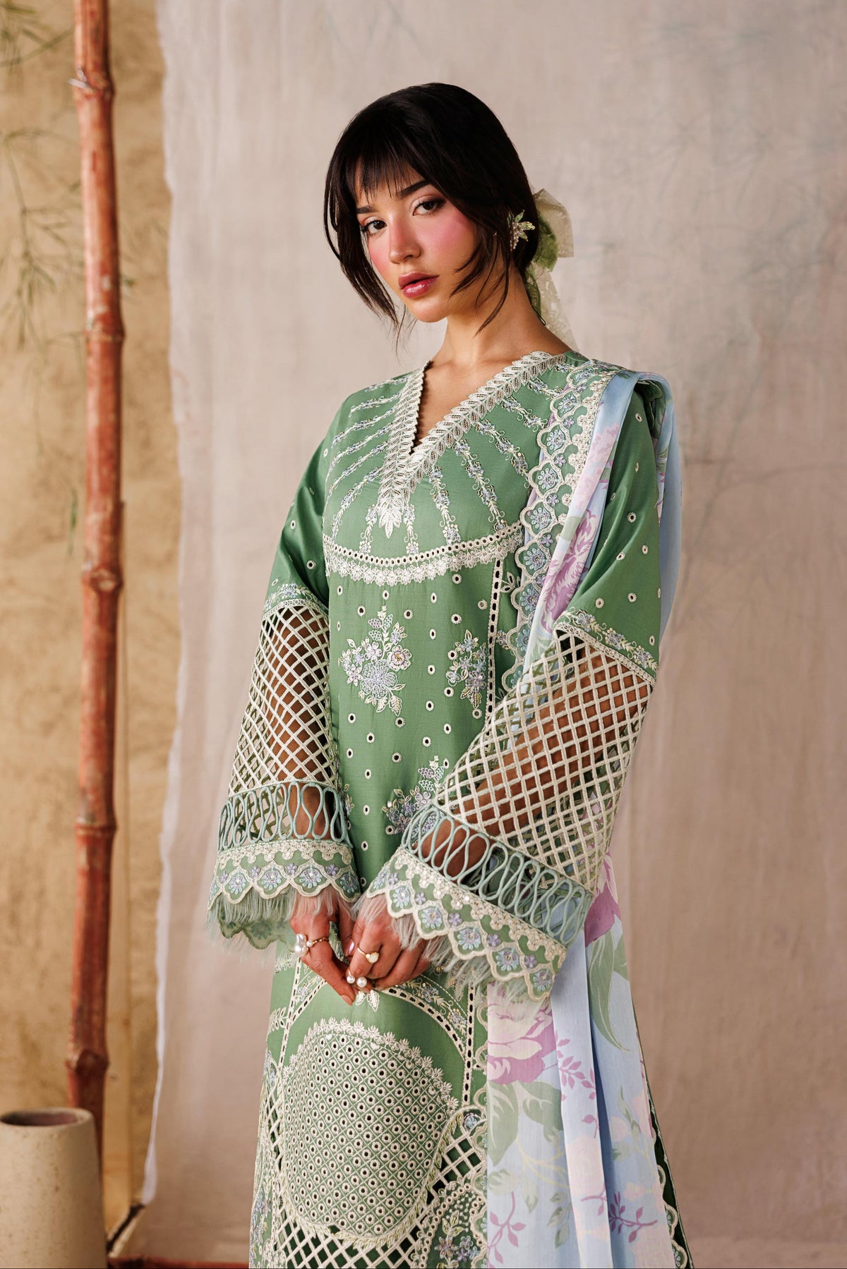 Woman wearing a green embroidered dress standing against a neutral background