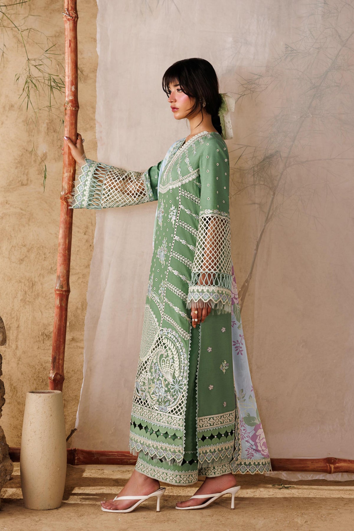 Woman in a green dress standing next to a bamboo frame with a plant in the background