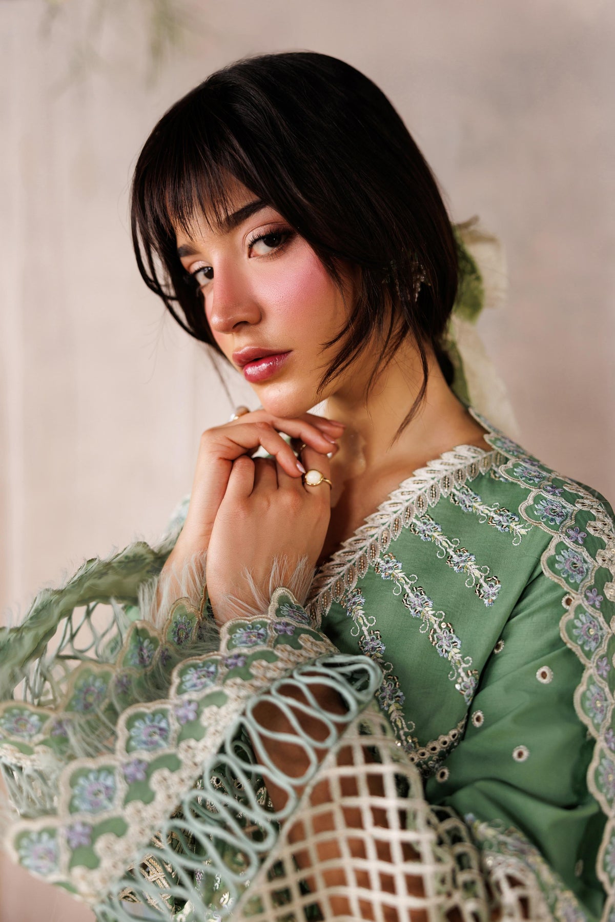 Woman wearing a green embroidered dress with a neutral background
