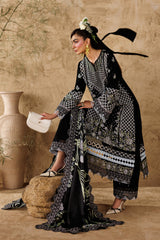 Woman in a black and white patterned dress standing against a beige wall with decorative vases.