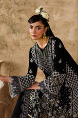 Woman in a black and white patterned dress with a floral headpiece, holding a white clutch, against a beige wall.