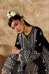 Woman in traditional embroidered outfit with floral headpiece against a beige wall.