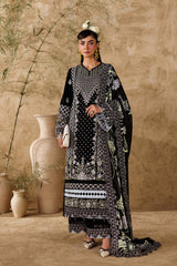 Woman in a black and white patterned outfit standing against a beige wall with decorative vases.