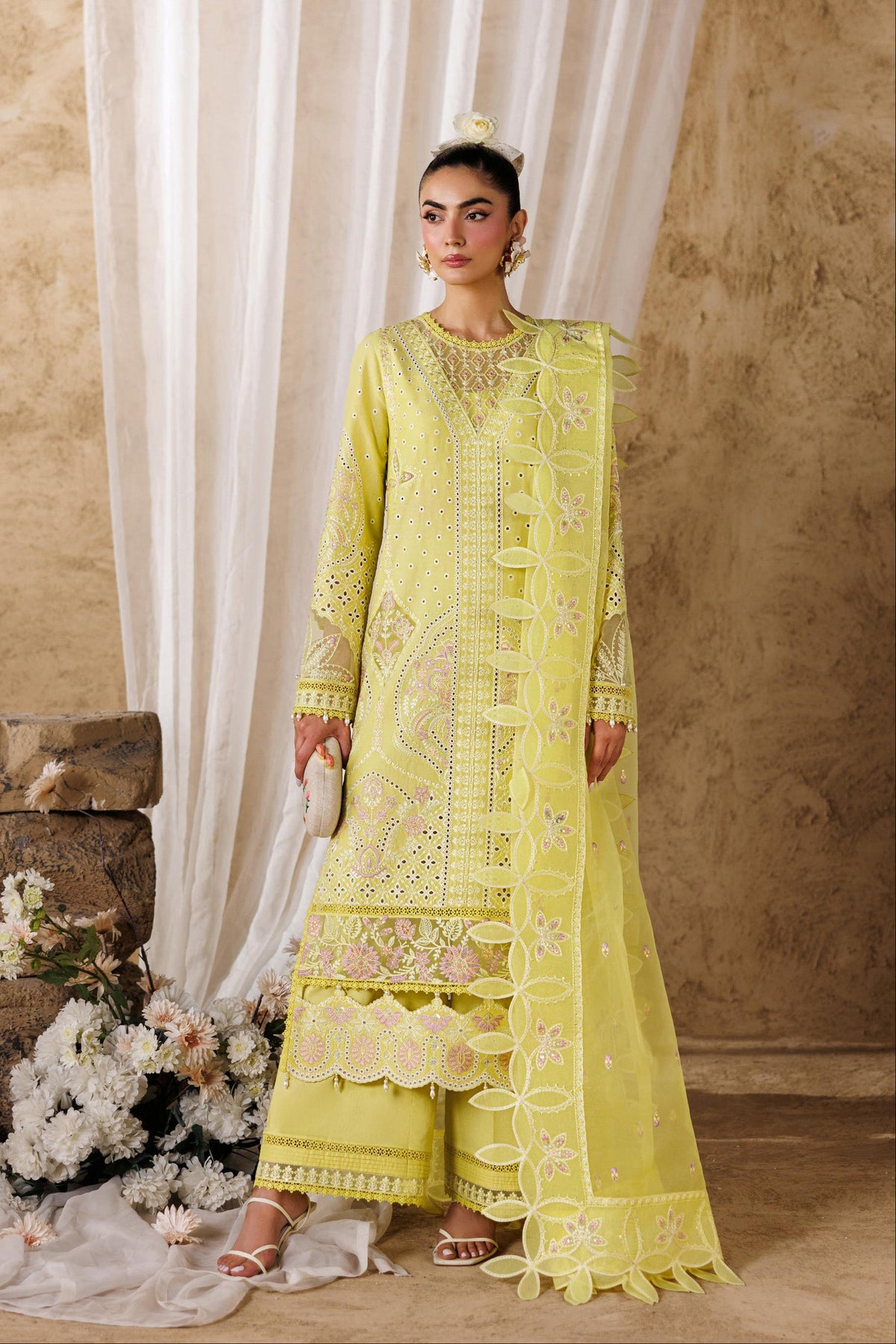 Woman wearing a bright yellow embroidered outfit with a neutral background