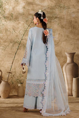 Woman in a light blue traditional outfit standing in a rustic setting with vases and plants.