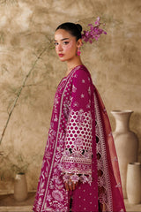 Woman in a vibrant pink and white traditional outfit with floral hairpiece against a textured beige wall.