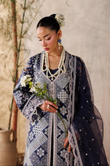 Woman in a patterned dress holding flowers against a neutral background