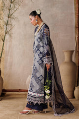 Woman in a traditional outfit standing in a room with decorative vases and plants.