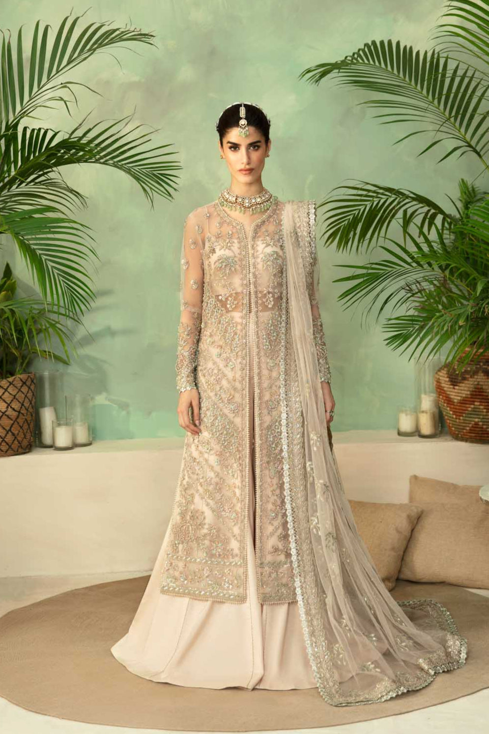 A woman wearing a beige and white embroidered dress with net and organza fabric, featuring hand embellishments.