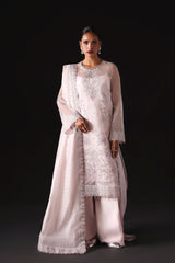 Woman wearing a light pink traditional outfit with intricate patterns on a black background