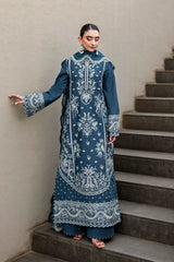 Woman in a blue embroidered traditional outfit standing on a staircase.