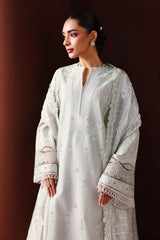 Woman wearing a light-colored embroidered dress against a dark background