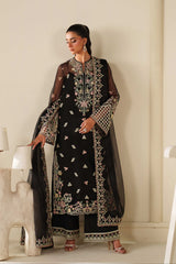 Woman wearing a black embroidered traditional outfit in a minimalistic room.